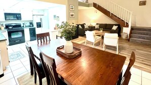 Amplia sala de estar con una mesa de comedor, sillas, un sofá y una escalera.