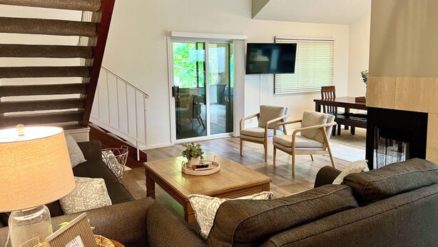 Una sala moderna con un sofá, sillones, una mesa de centro y un televisor.