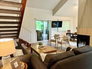 A living room with a sofa, chairs, a coffee table, a TV, and a fireplace.