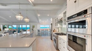 Une cuisine moderne avec des meubles blancs, des appareils en acier inoxydable et un grand îlot central.