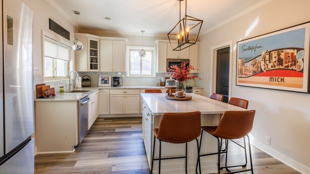 A modern kitchen with a central island, bar stools, and a hanging light fixture. - Welcoming updated modern 3-bedroom house in Mount Clemens (Mount Clemens)