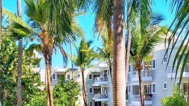 A resort with a swimming pool surrounded by palm trees and well-maintained landscaping. - Sol Caribe Primavera Pool (Punta Cana)