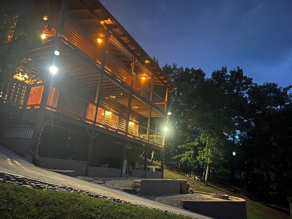 A multi-story building with a wooden exterior and multiple illuminated windows. - Lakefront covered dock sleeps 12 (Dandridge)