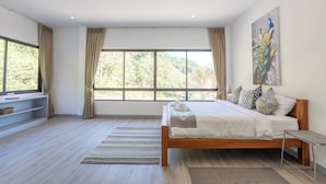 Un dormitorio moderno con un ventanal grande, una cama de madera y un cuadro en la pared.