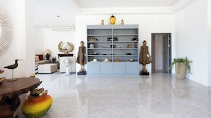 Un salón amplio con un diseño moderno, que incluye una gran estantería, una escultura decorativa de un pájaro y un jarrón esférico original.