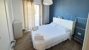 Een slaapkamer met een bed, witte gordijnen, een plafondlamp en een blauwe muur.