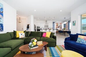 A modern living room with green sofas, a coffee table, and colorful cushions.