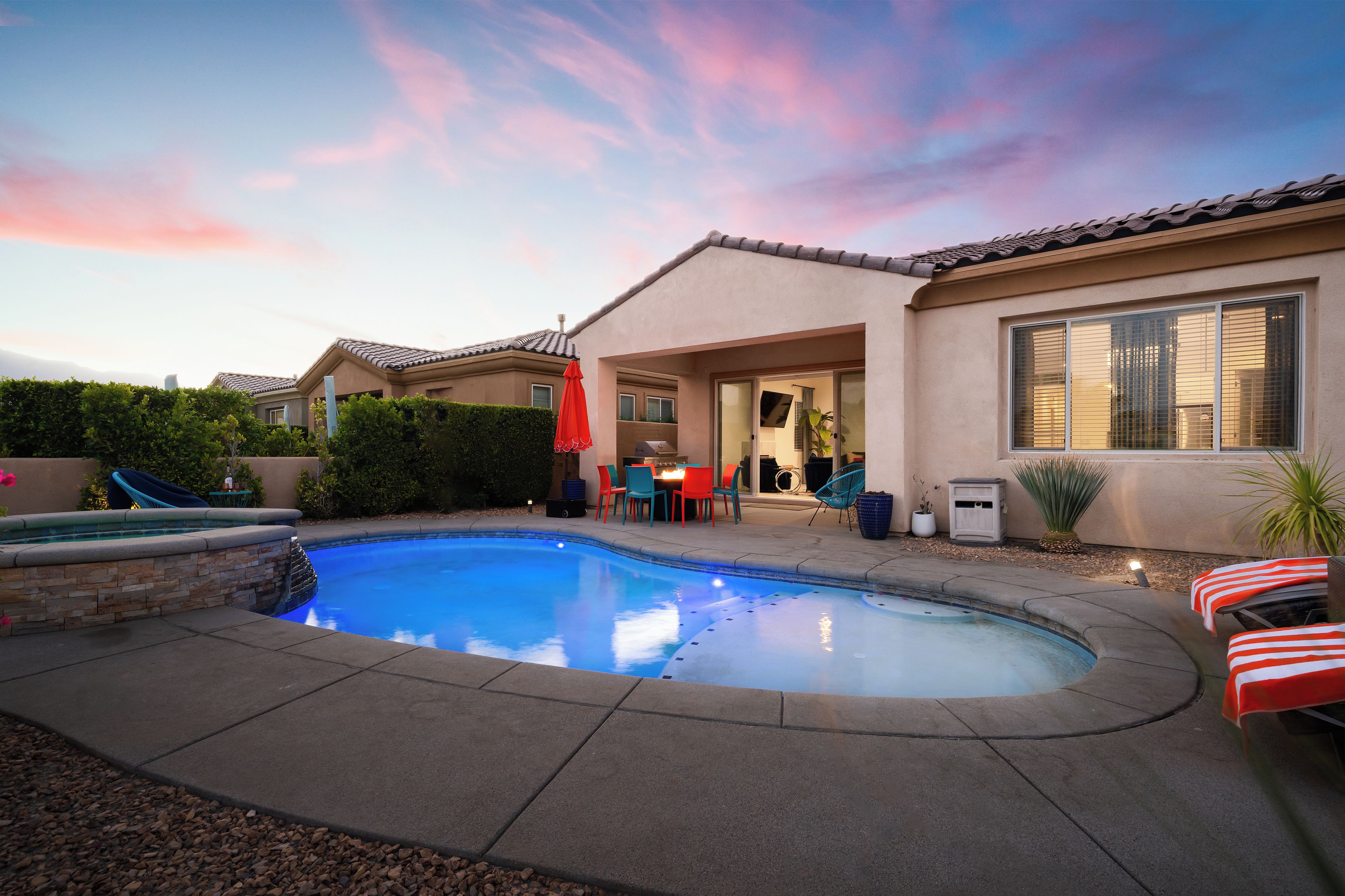 A residential backyard with a swimming pool, patio furniture, and a covered outdoor seating area.
