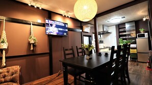 A dining area with a wooden table, chairs, a TV mounted on the wall, and a hanging light fixture. - TraditionalJapanese Vacation house near to metro station, 4 bedroom Multiple bath (墨田区)