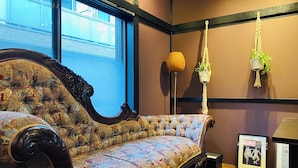 A vintage sofa with intricate patterns, a large window with a view of buildings, and a macramé plant hanging on the wall. - TraditionalJapanese Vacation house near to metro station, 4 bedroom Multiple bath (墨田区)