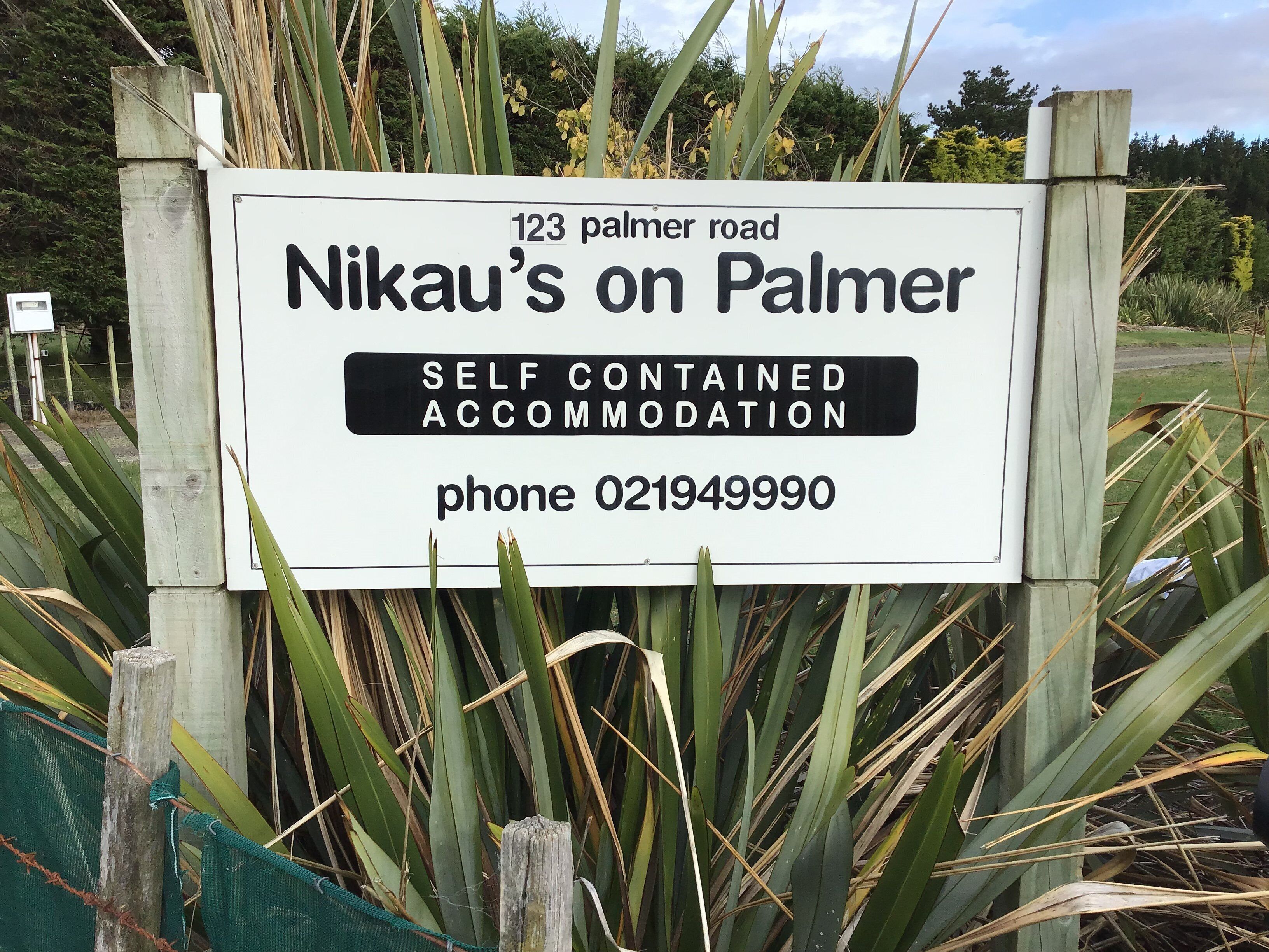 A sign for 'Nikau's on Palmer' indicating self-contained accommodation with a contact number.