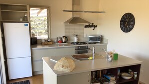 A modern kitchen with a central island, a microwave, a kettle, and a sink. - Ready for a cosy Beach holiday? (Foxton Beach)