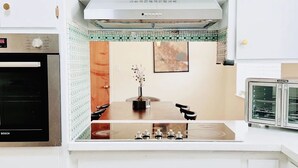 Una cocina con armarios blancos, un horno Bosch, un microondas integrado y una encimera con un lavabo.