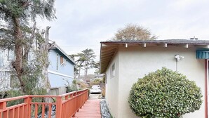 Un estrecho sendero de madera que conduce a una casa con un pequeño jardín y una barandilla roja.