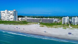 Ein Hotel direkt am Strand mit mehreren Gebäuden, einem Sandstrand und Blick auf den Ozean.