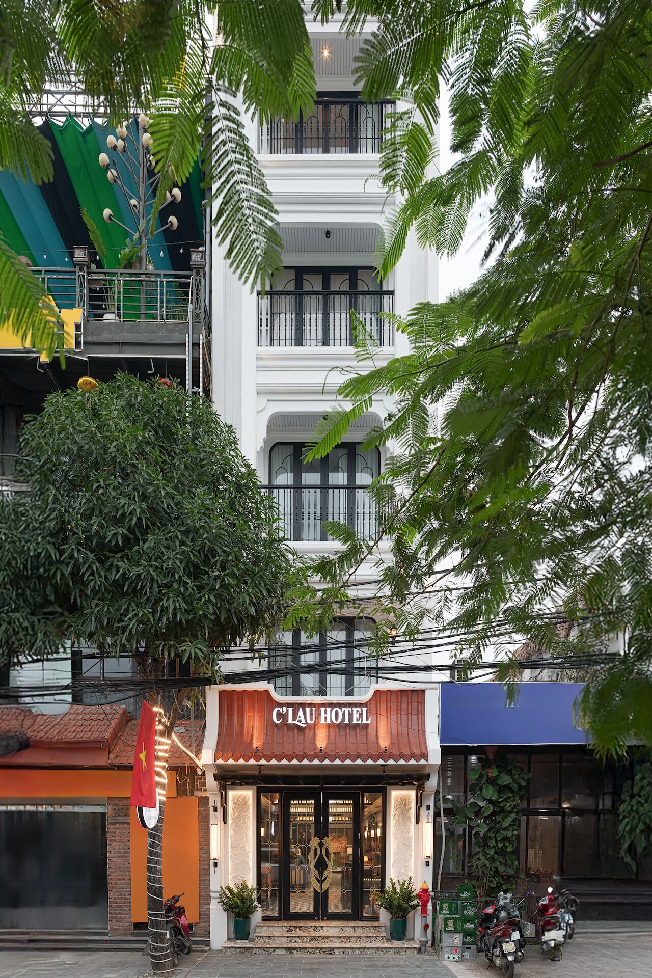 Un hôtel à la façade traditionnelle, doté d’un balcon avec une balustrade et d’un drapeau.