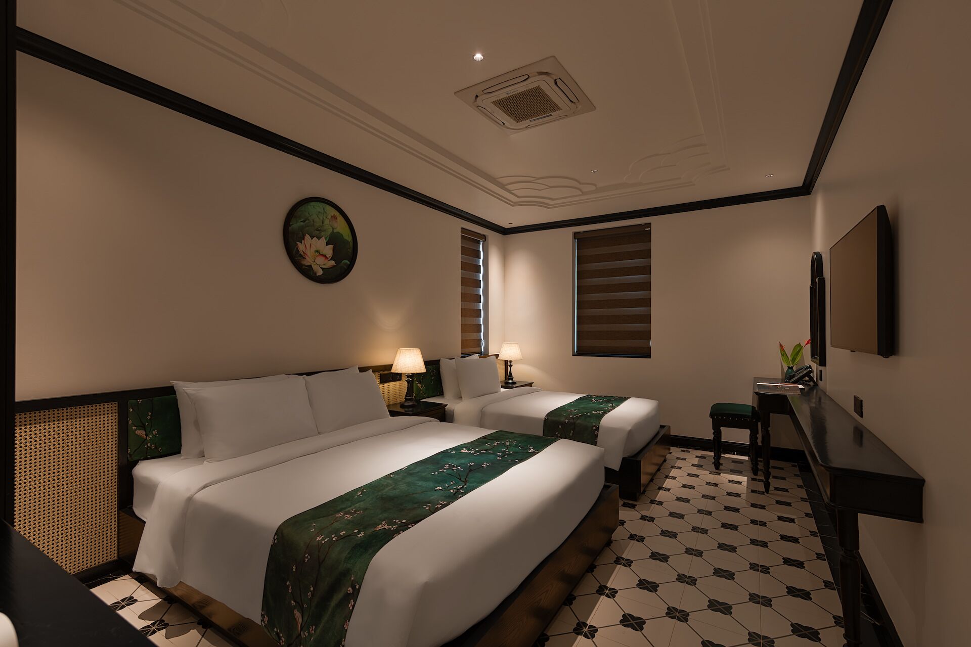 Een hotelkamer met twee bedden, een bureau, een stoel, een televisie en een schilderij aan de muur.