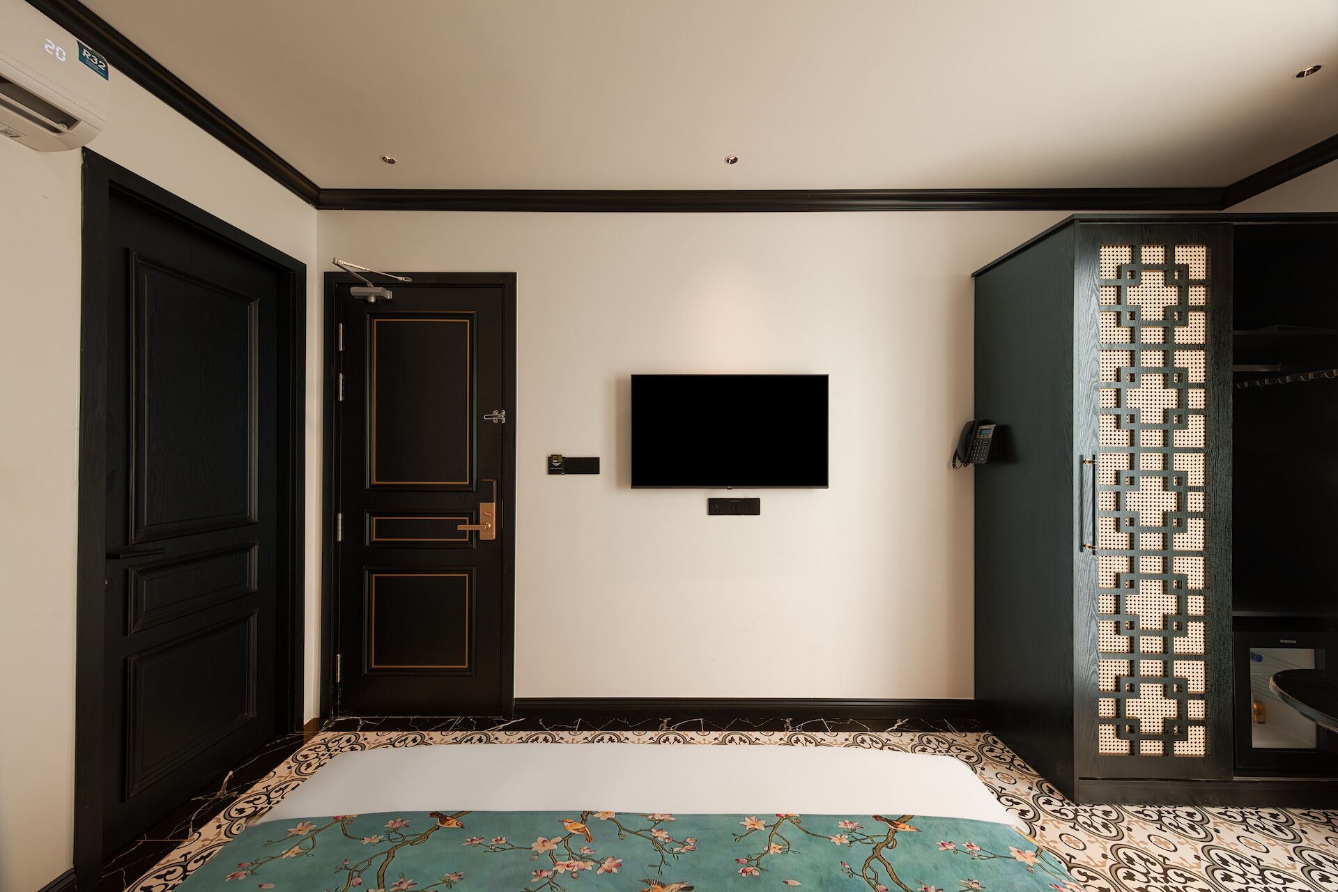 A hotel room with a bed, a TV mounted on the wall, a wardrobe, and a door.