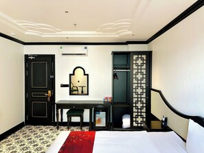 A hotel room with a bed, a desk, a chair, a mirror, a wardrobe, and a bathroom. - C'Lau Hotel Ninh Binh - A Gem Nestled in Ancient Quarter (Hoa Lu)