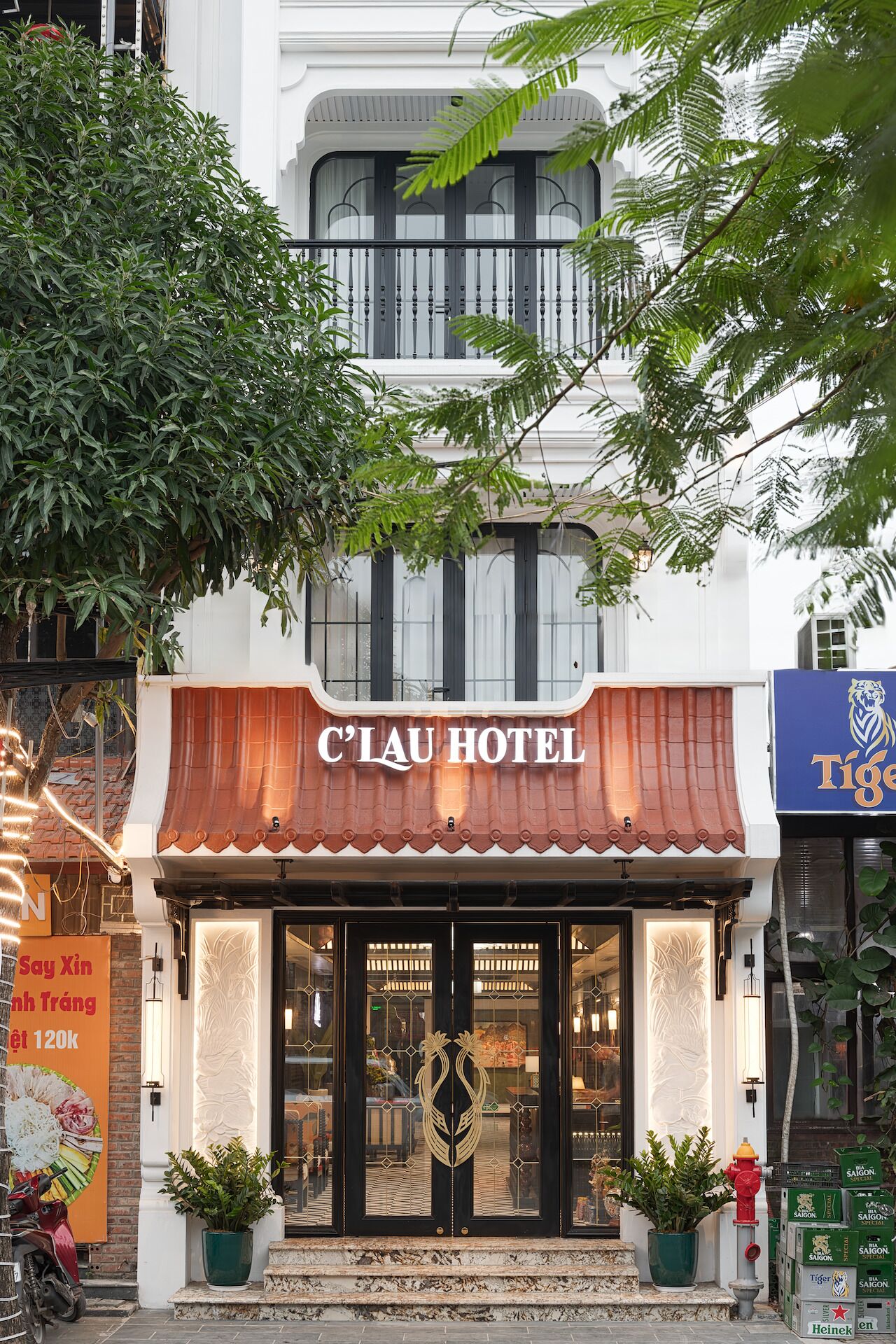 L’extérieur de l’hôtel C’LAU présente une façade de style traditionnel, de grandes fenêtres et une enseigne.