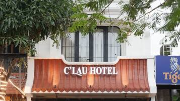 L’extérieur de l’hôtel C’LAU présente une façade de style traditionnel, de grandes fenêtres et une enseigne.