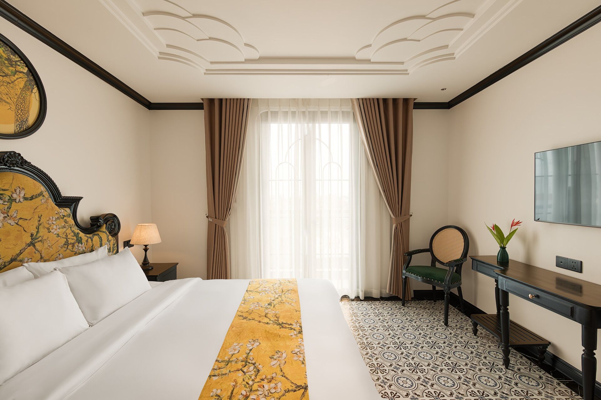 A hotel room with a bed, a desk, a chair, and a large mirror.