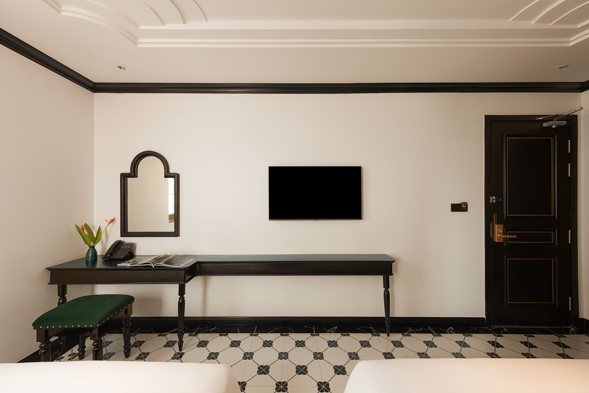 Een hotelkamer met een groot bed, een bureau met stoel, een spiegel, een flatscreen-tv en een deur.