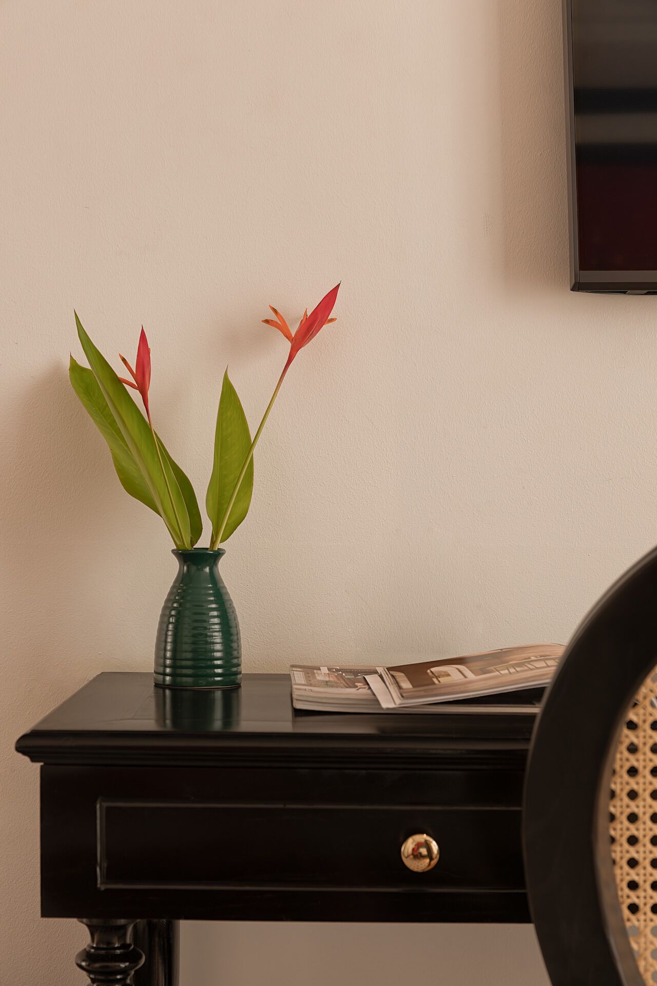 A black desk with a green vase containing red and green leaves.