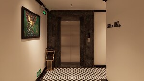 Un pasillo con piso estampado, una obra de arte enmarcada en la pared y un letrero de indicaciones.