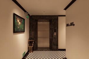 A hallway with a patterned floor, a framed artwork on the wall, and a directional sign.