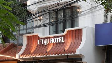 A hotel entrance with a traditional design, a visible address number, and parked motorcycles outside.