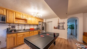 Eine Küche mit Holzausstattung, einem Tischtennis-Tisch, einem Kühlschrank und einer Kaffeestation.