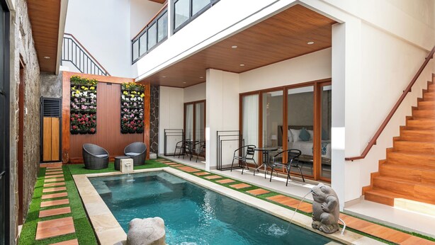 Un espace piscine résidentiel moderne agrémenté d’une fontaine en pierre, d’un escalier en bois et d’un coin salon avec des meubles d’extérieur.