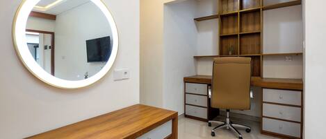 Un espacio de oficina moderno con un escritorio de madera, un espejo redondo, una silla y estanterías empotradas.
