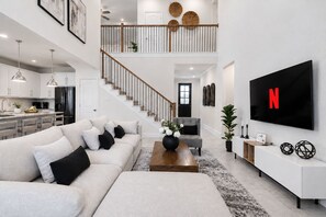A modern living room with a sofa, coffee table, and a flat-screen TV mounted on the wall.