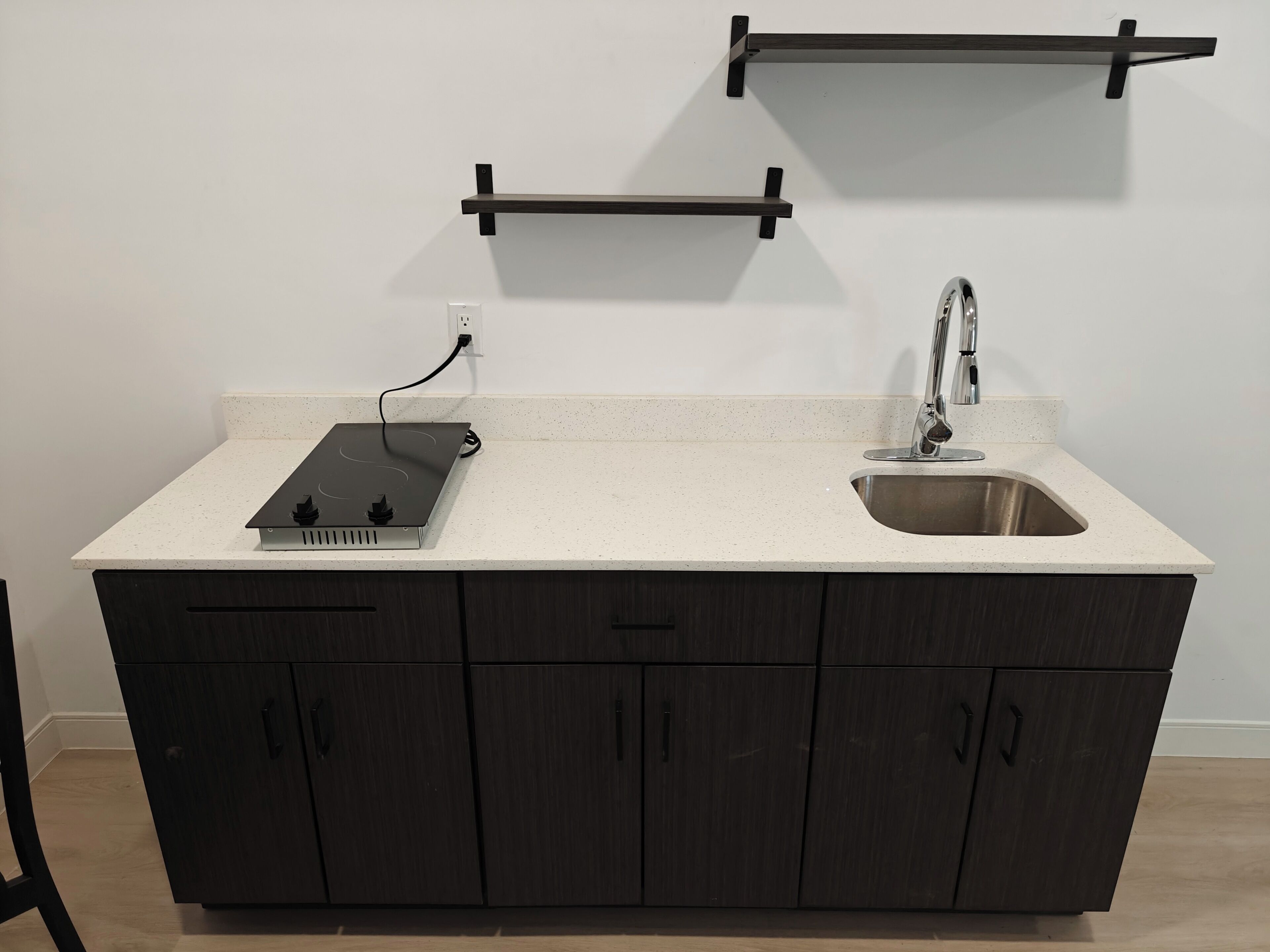 A kitchen with a countertop, a sink, a stove, and dark wooden cabinets.