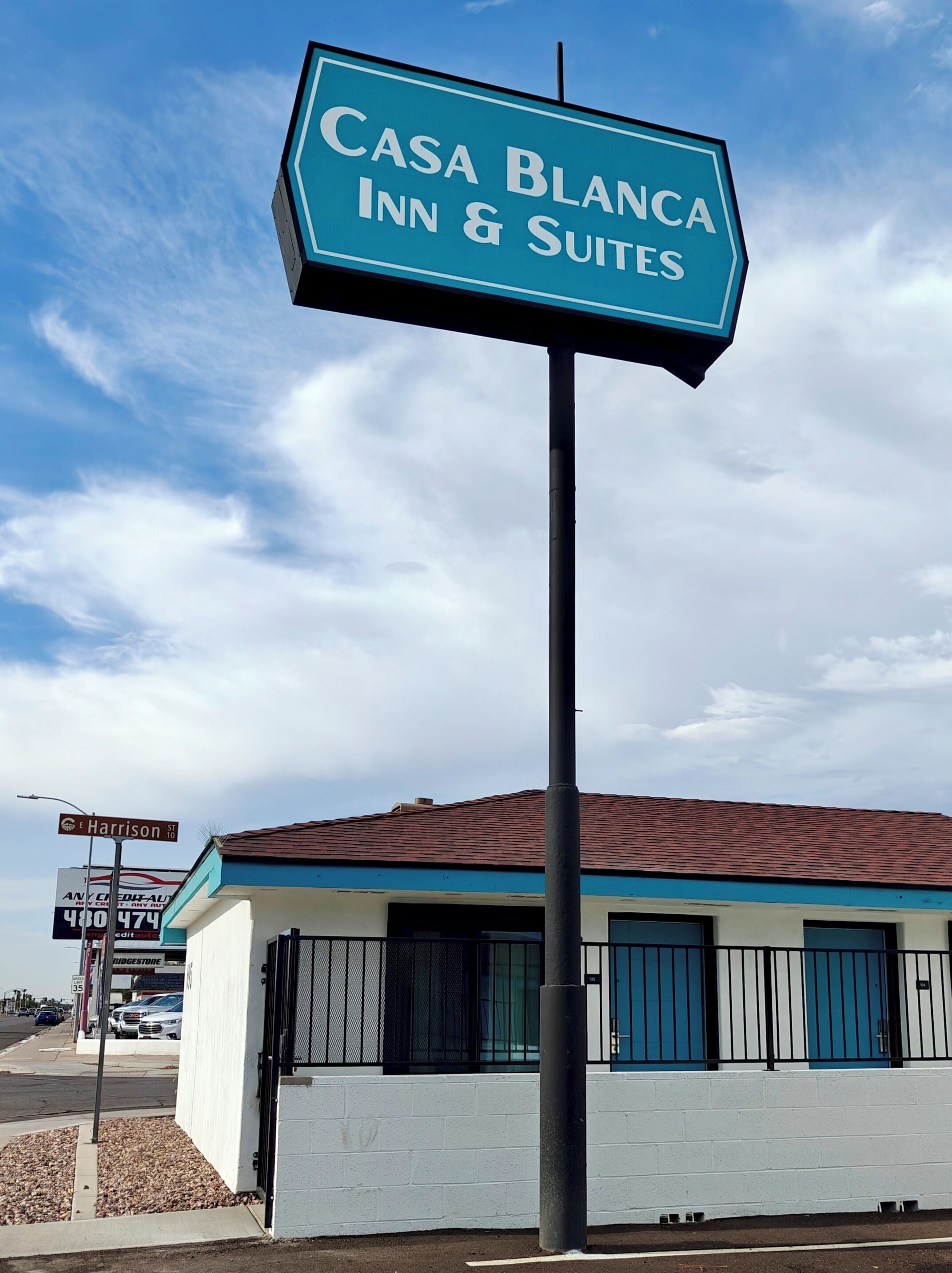 Letrero de 'Casa Blanca Inn & Suites', con vista clara del exterior del edificio, incluyendo fachada blanca, detalles azules y techo de tejas rojas.