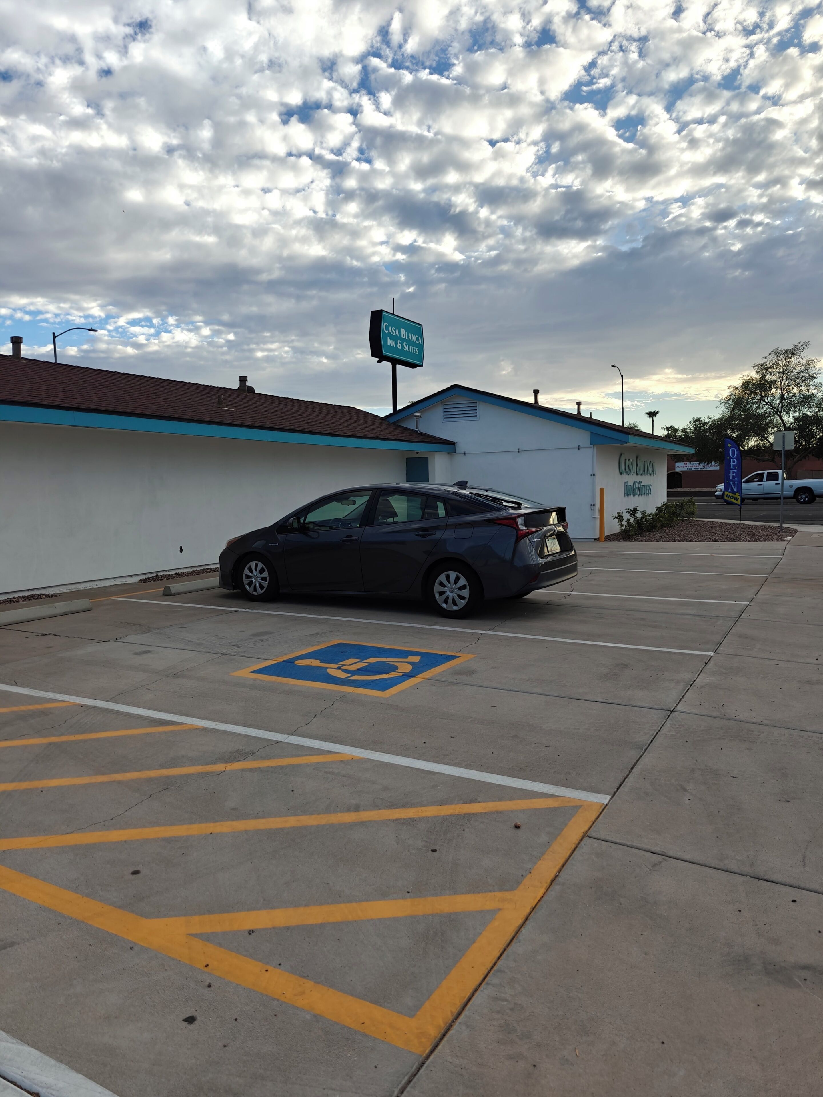A parking lot with a handicapped parking space, a sign for Casa Blanca Inn & Suites, and a building with a blue roof.