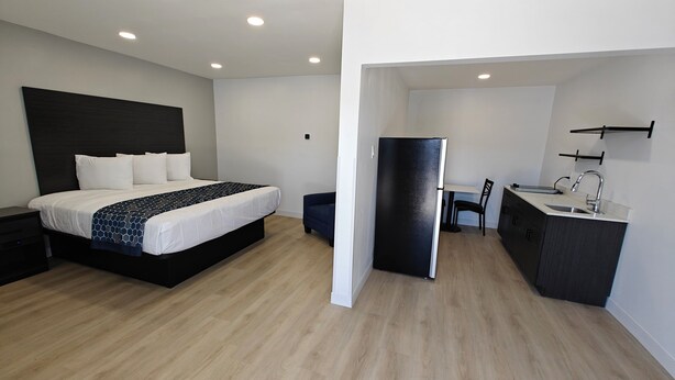 A modern hotel room with a bed, a small kitchenette, and a dining area. - Casa Blanca Inn and Suites (Chandler)