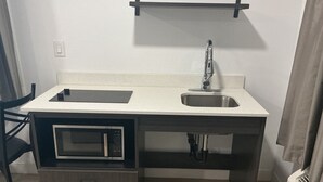 A compact kitchenette with a microwave, sink, and storage drawers. - Casa Blanca Inn and Suites (Chandler)