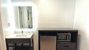 A compact bathroom with a sink, mirror, and built-in microwave. - Casa Blanca Inn and Suites (Chandler)