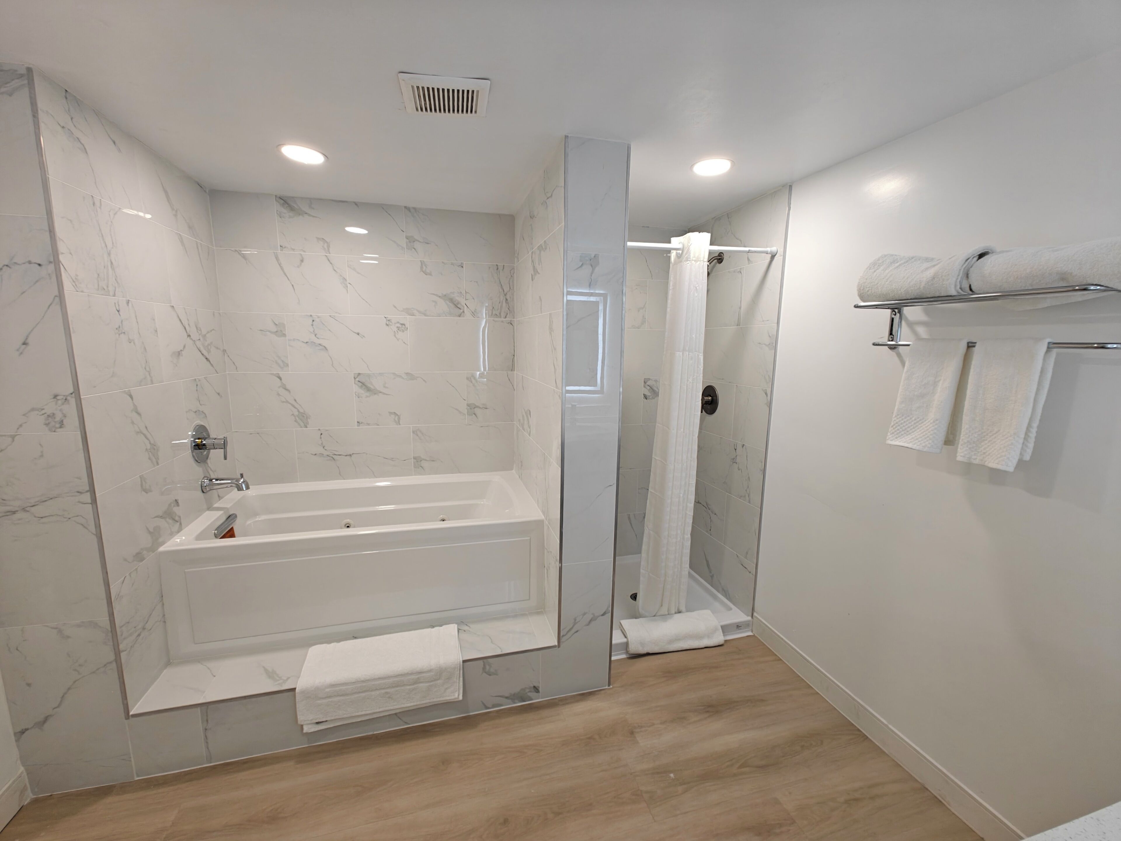 A modern bathroom with a bathtub, shower, and a glass-enclosed shower area.
