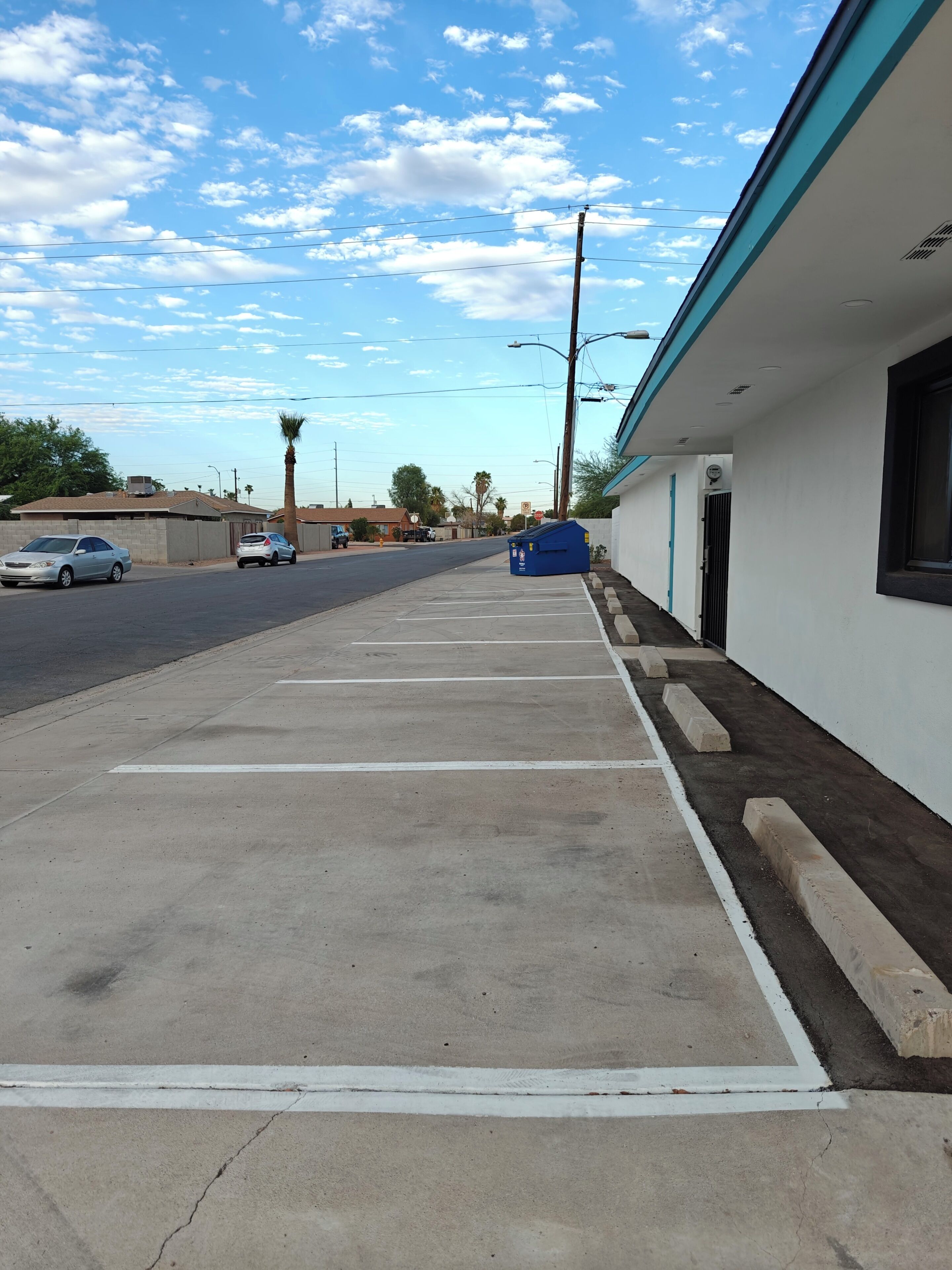 A parking lot with concrete surfaces and marked parking spaces.