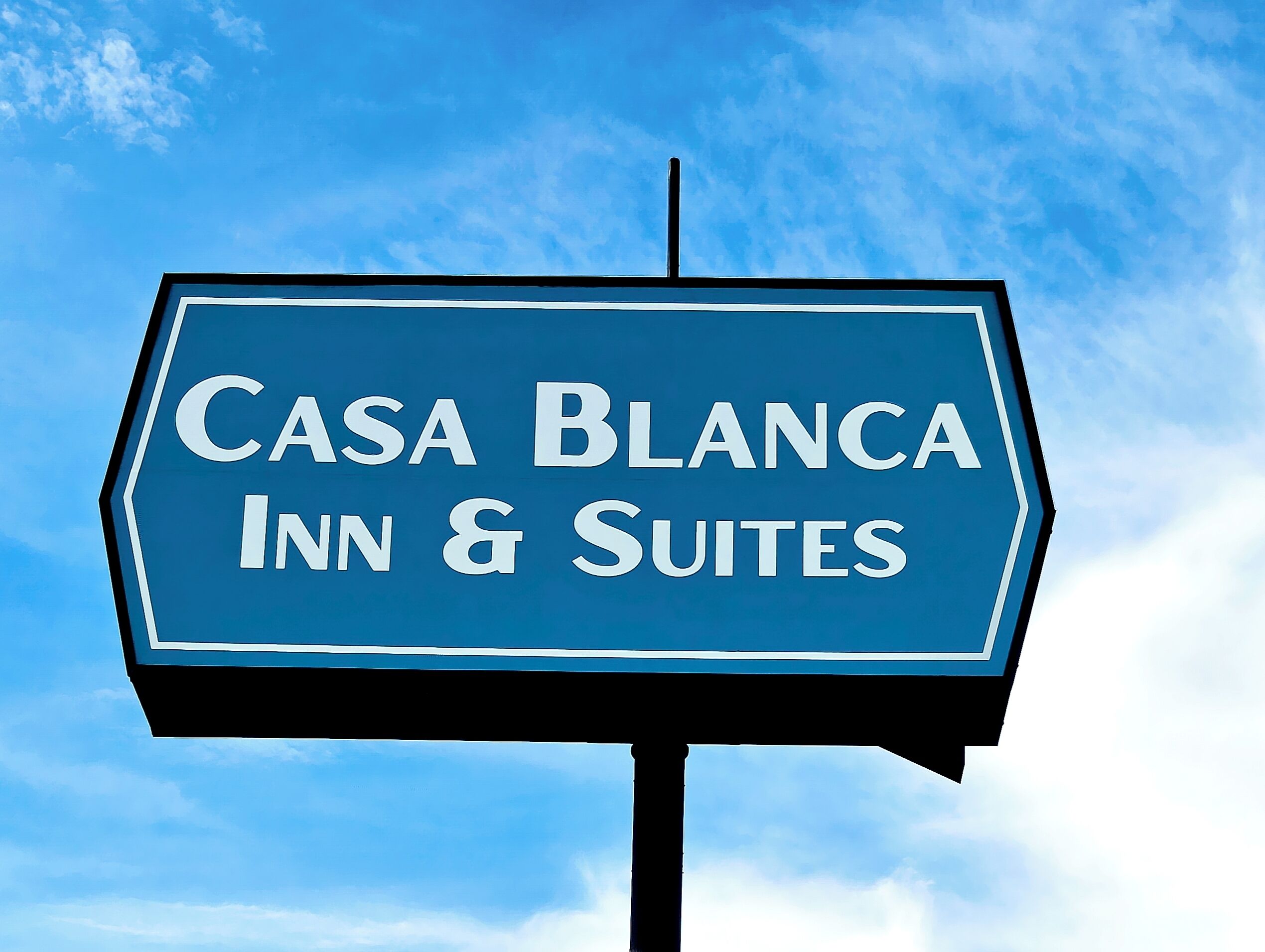 A sign for 'Casa Blanca Inn & Suites' against a clear blue sky.