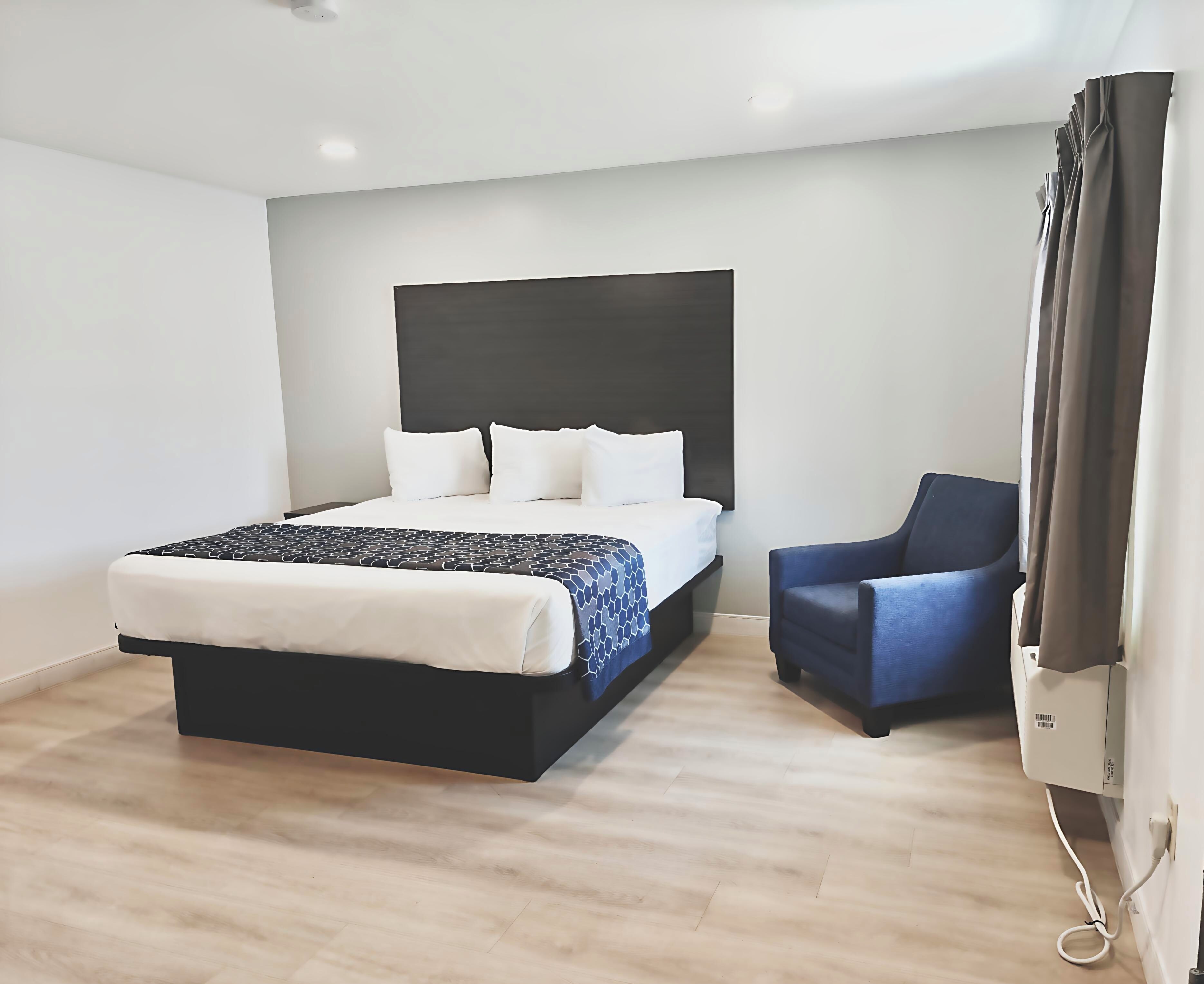 Habitación de hotel moderna con cama, una silla y televisor de pantalla plana.