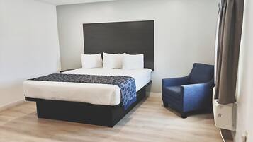 A modern hotel room with a bed, a chair, and a flat-screen TV.