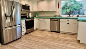 A modern kitchen with stainless steel appliances, white cabinets, and a green countertop. - Sun House - your own private getaway (Phoenix)
