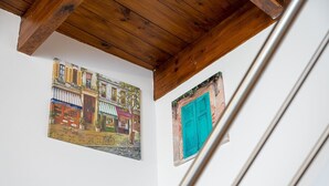 Un escalier avec un plafond en bois et un mur orné de deux œuvres d’art encadrées.