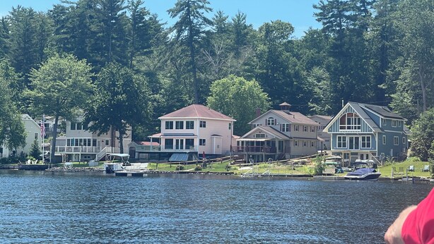 A lakeside residential area with houses along the water's edge, a dock, and a boat.