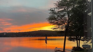 A lakeside view with a dock, picnic tables, and an American flag.